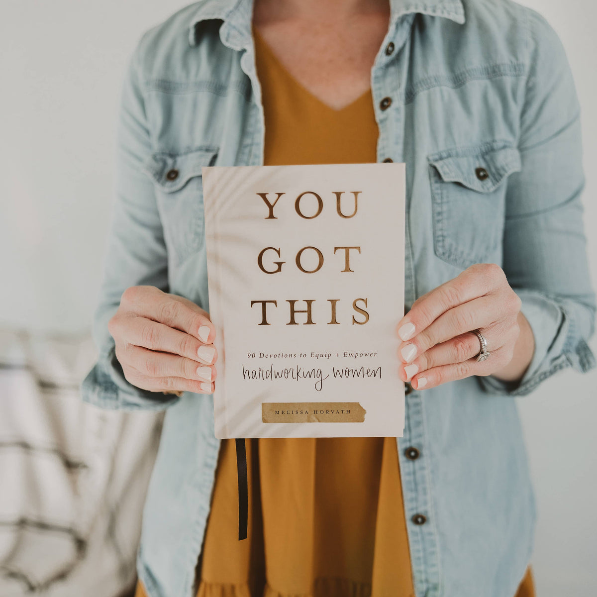 Person holding a book titled 'You Got This' with a motivational message.